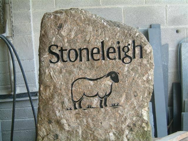 Rustic stone house sign reading Stoneleigh with a carved sheep