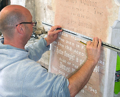 A mason setting out the lettering on an old sandstone headstone
